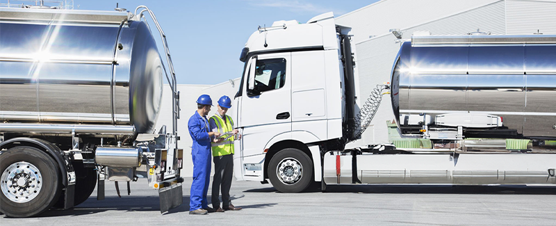 Técnicos industriales inspeccionando camiones cisterna en entorno logístico, como parte del control de medios y procedimientos en transporte de mercancías peligrosas