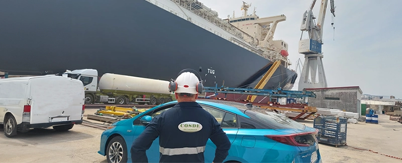 Técnico de COSDE Tecnológico supervisando operaciones portuarias junto a un buque gasero, como parte de procedimientos OPEX en transporte de materiales peligrosos